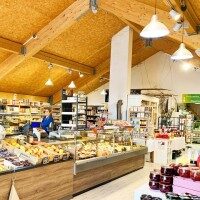 Innenansicht eines Hofladens mit frischem Obst, Gemüse, Käse und regionalen Produkten
