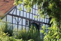 Hof Bögel-Windmeier Ein schönes Fachwerkhaus mit grünen Bäumen und Büschen im Vordergrund