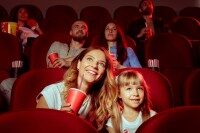 Apollo Kino Ibbenbüren Mehrere Personen sitzen auf roten Kinosesseln und schauen gespannt und glücklich einen Film an