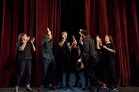 Schauspieler stehen auf der Bühne, klatschen sich ab und freuen sich