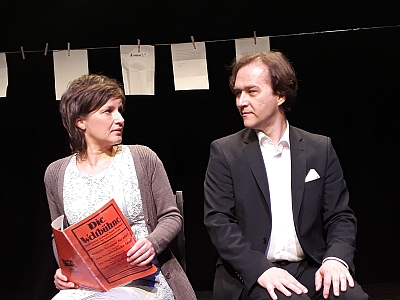 Theater Eine Frau und ein Mann sitzen auf einer Bühne und schauen sich an.