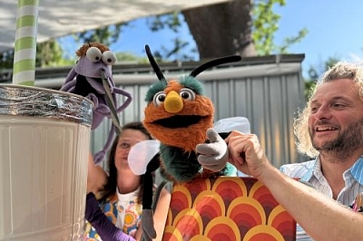 Das Bild zeigt die Szene eines Kindertheaterstücks mit einer Mücken-Handpuppe und einer Hummel-Handpuppe. 