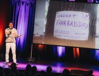 Dr. Dolittle Schauspieler auf einer Bühne vor einer Leinwand die ein Schild mit der Aufschrift
