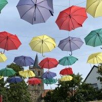 Oberer Markt in Ibbenbüren. Bunte Fähnchen hängen an einem Masten und Menschen machen einen Einkaufsbummel durch die Stadt