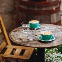 Kaffeetisch in Holzoptik mit zwei Gläsern mit Wasser und zwei Tassen mit Kaffee