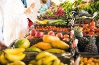 Frisches Obst und Gemüse in Körben und eine Frau bestellt etwas