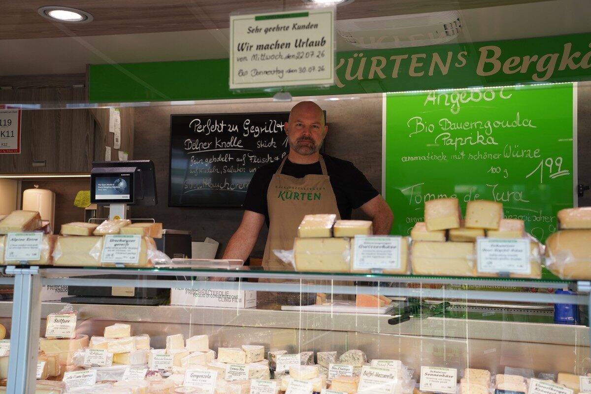 Käsestand auf dem Wochenmarkt mit einen Mitarbeiter.